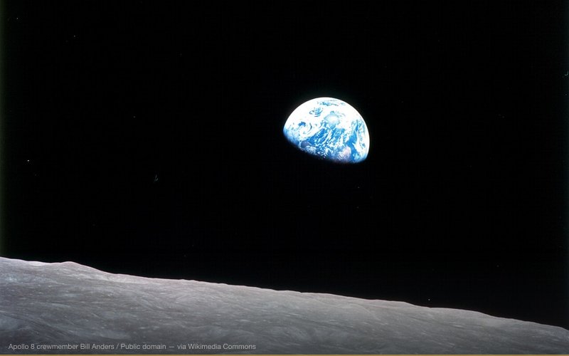 This view of the rising Earth greeted the Apollo 8 astronauts as they came from behind the Moon after the fourth nearside orbit. Earth is about five degrees above the horizon in the photo. The unnamed surface features in the foreground are near the eastern limb of the Moon as viewed from Earth. The lunar horizon is approximately 780 kilometers from the spacecraft. Width of the photographed area at the horizon is about 175 kilometers. On the Earth 240,000 miles away, the sunset terminator bisects Africa. — related to We Live in the Matrix